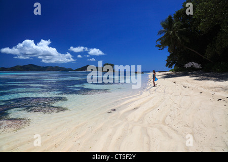 Frau in blau Sarong zu Fuß entlang des Strandes in der Nähe von Anse Source d ' Argent auf La Digue auf den Seychellen Stockfoto