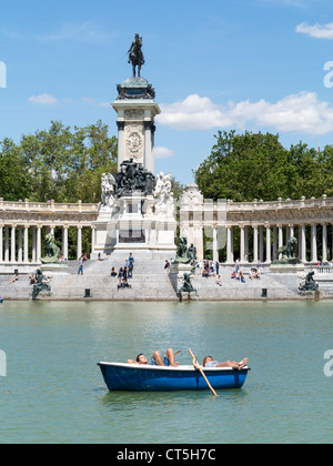 Paar, faulenzen, Sonnenbaden in einem Ruderboot vor Denkmal für König Alfonso XII, Parque del Retiro, Madrid Stockfoto