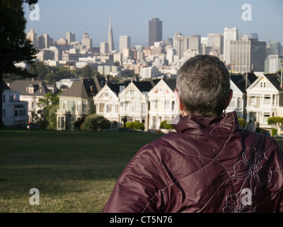 Weiblichen Blick auf die Painted Ladies, beherbergt Victorian in der Steiner Street, gegenüber dem Alamo Square Park in San Francisco Stockfoto