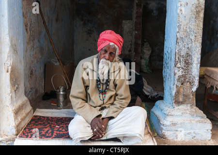 Alten indischen Mann mit einem roten Turban, sitzt vor einer Tür, Pushkar, Rajasthan, Indien Stockfoto