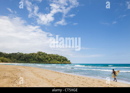 Surfer zu Fuß entlang des Meeres an Assistenten Strand (erste) auf Isla Bastimentos, Bocas del Toro, Panama. Stockfoto