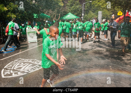 Jugendliche abkühlen mit Wasser besprüht von einem ordnungsgemäß aufgestellter Hydranten bei der Eröffnung des einen Sommer Spielstraße Stockfoto