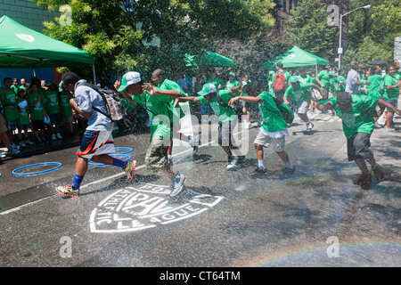 Jugendliche abkühlen mit Wasser besprüht von einem ordnungsgemäß aufgestellter Hydranten bei der Eröffnung des einen Sommer Spielstraße Stockfoto