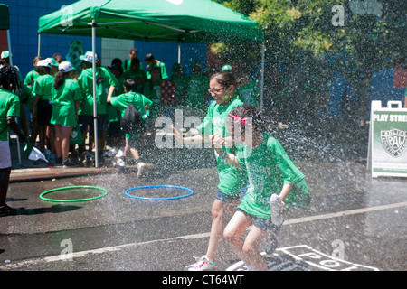 Jugendliche abkühlen mit Wasser besprüht von einem ordnungsgemäß aufgestellter Hydranten bei der Eröffnung des einen Sommer Spielstraße Stockfoto