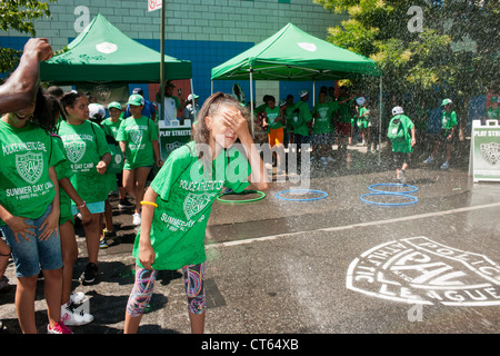 Jugendliche abkühlen mit Wasser besprüht von einem ordnungsgemäß aufgestellter Hydranten bei der Eröffnung des einen Sommer Spielstraße Stockfoto