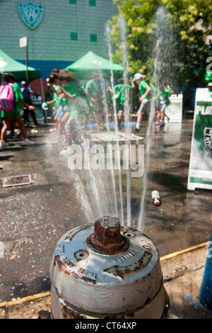 Jugendliche abkühlen mit Wasser besprüht von einem ordnungsgemäß aufgestellter Hydranten bei der Eröffnung des einen Sommer Spielstraße Stockfoto