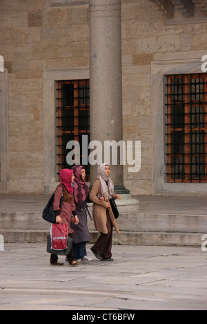 Junge muslimische Frauen gehen in den Innenhof des Sultan Ahmed Mosque, Sultanahmet, Istanbul, Türkei Stockfoto