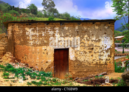 Adobe-Backstein-Haus in Schutt und Asche unter Vegetation und bergige Landschaft in Oaxaca, Mexiko Stockfoto