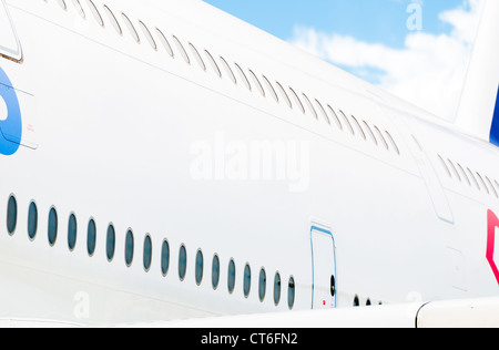 Seitenansicht des weißen Passagierflugzeug mit zwei Reihen von Fenstern und blau bewölktem Himmel im Hintergrund. Ort für Kopie. Stockfoto