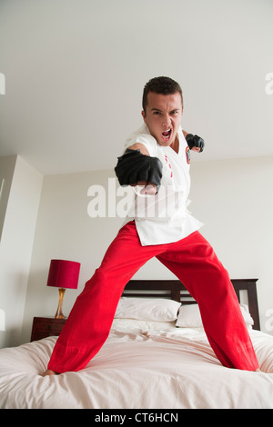 Porträt eines aggressiven jungen Mannes üben Kung-Fu auf Bett Stockfoto