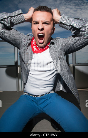 Frustrierte junge Mann seine Haare ziehen und schreien Stockfoto