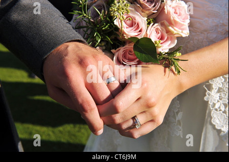 Hochzeit des Paares Hände tragen Ringe mit rosa Blumenstrauß Stockfoto