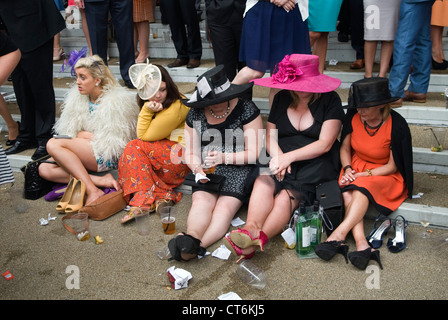 Müde erschöpft, schmerzende Füße, abgenutzte, unbequeme Schuhe, eine Gruppe von Frauen, die sich hinsetzen und auf ihre Füße schauen. HOMER SYKES AUS DEN 2012 2010ER JAHREN Stockfoto