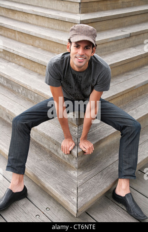 Porträt von glücklich junger Mann sitzt auf Holzstufen Stockfoto
