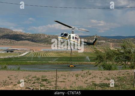 Ein Feuerwehrmann Hubschrauber eilt um zu helfen, ein Lauffeuer, tragen einen großen Eimer mit Wasser zu löschen. Stockfoto