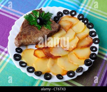 Kalbfleisch mit gebratenen Kartoffeln auf einem Teller Stockfoto