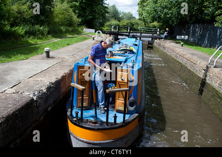 Ein Mann prüft eine Karte, als er seinen engen Schiff durch eine Schleuse entlang der Grand Union Canal in Watford, England navigiert. Stockfoto