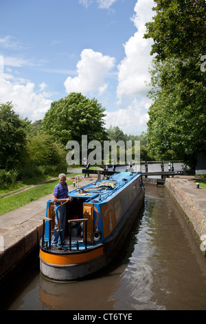 Ein Mann navigiert seinen engen Schiff durch eine Schleuse entlang der Grand Union Canal in Watford, England. Stockfoto