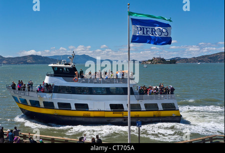 ALCATRAZ Pier 39 Fahne mit Alcatraz Gefängnis Insel hinter, Tour boot Zurückbringen von Bay Cruise Embarcadero, San Francisco, Kalifornien, USA Stockfoto