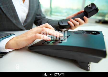 Weibliche Hand mit Telefonhörer und Einwahl-Nummer Stockfoto