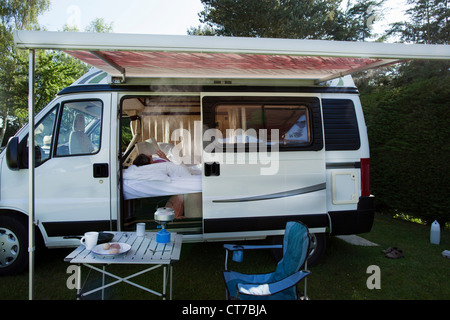 Reife Frau trinken Lesebuch in Wohnmobil Stockfoto