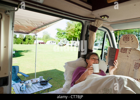 Reife Frau liest in Wohnmobil Stockfoto