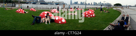 Park-Geher entspannen während einer Hitzewelle auf dem Rasen auf dem Christopher Street Pier im Hudson River Park in New York Stockfoto