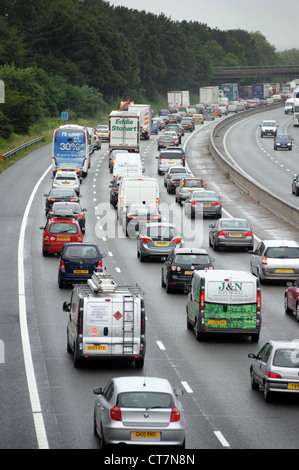 STARKEN VERKEHR AUF DER AUTOBAHN M6 AUTOBAHN IN DER NÄHE VON STAFFORD WIEDER WARTESCHLANGEN MARMELADEN TRANSPORTWAGEN BIKER WARTESCHLANGEN AUTOFAHREN BÄUME NOISE BARRIER UK Stockfoto