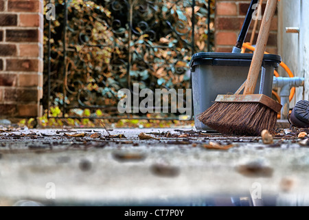 Herbstlaub auf dem Weg mit Hof Besen und Eimer Stockfoto