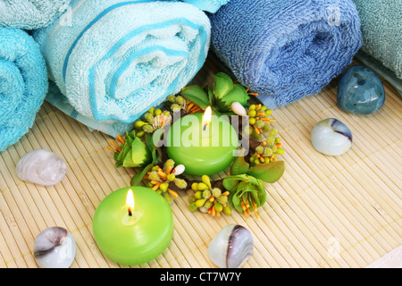 Stapel von Handtüchern, Kerzen, Steinen auf Matten Hintergrund. Stockfoto