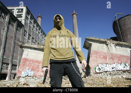 Ein Teenager mit einer Pistole vor einer Fabrik Ruine