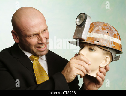 Mann hält Puppe Kopf mit Bergleute Helm Stockfoto