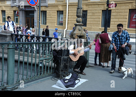 Mann spielt Gitarre für Besucher am Ende der Brücke über den Gribojedow-Kanal in St. Petersburg, Russland. Stockfoto