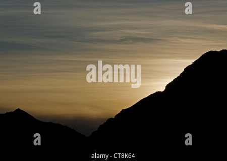 Die untergehende Sonne hinter einem Alpenkamm Stockfoto