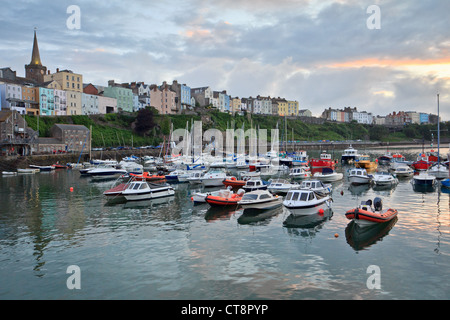 Tenby, Pembrokeshire, showing the Harbour with boats at sunset, overlooked by St Mary's Church and colourful Victorian houses. Stockfoto