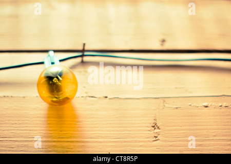 Klar orange Zeichenfolge Glühbirne hängen an einem Holzzaun Stockfoto