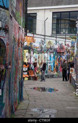 Gruppe von Mädchen spritzen Graffiti an einer Wand in Werregaren Straat - Straße in Gent, wo Graffiti legal Gent-Brüssel ist Stockfoto