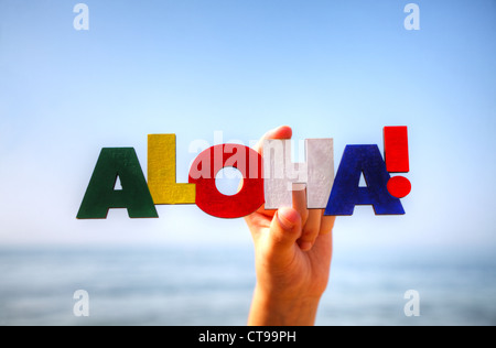 Weiblichen Hand mit bunten Wort "Aloha" vor blauem Hintergrund Stockfoto