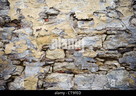 Eine strukturierte alte Steinmauer mit abblätterndem Putz und verwitterter Oberfläche schafft ein rustikales und Vintage-Aussehen Stockfoto