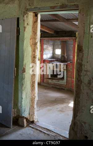 Auf der Suche durch einen Eingang zu einem alten Ofen großzügig einen verlassenen und verfallenen Bauernhaus in der Western Australian outback. Stockfoto