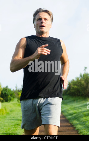 Ein Mann läuft entlang eines Weges tragen einen schwarzen Tank-Top und graue Shorts. Stockfoto