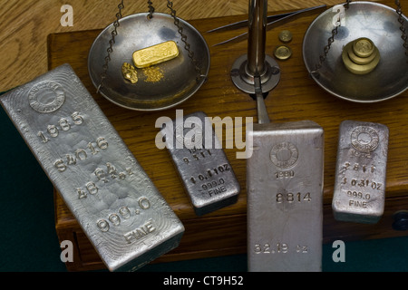 Silber-Barren - Goldbarren, Gold-Nugget und Goldstaub auf antiken Balance Skala. Messing Gewichte auf der anderen Seite Stockfoto