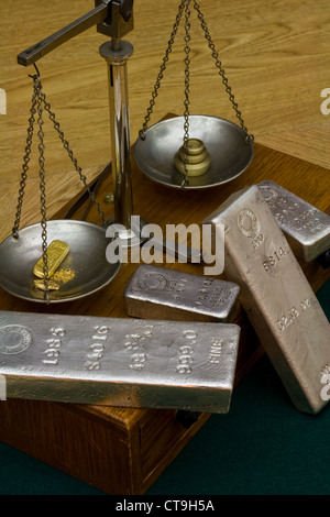 Silber-Barren - Goldbarren, Gold-Nugget und Goldstaub auf antiken Balance Skala. Messing Gewichte auf der anderen Seite Stockfoto