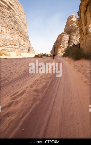 Eine Figur folgt die Reifenspuren von Jeeps durch ein Tal in Wadi Rum, Jordanien Stockfoto