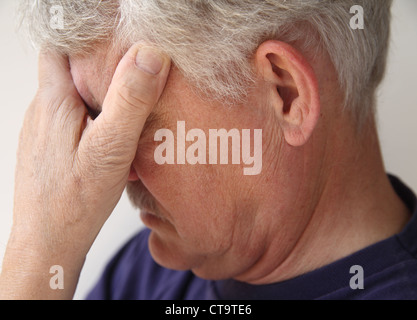 ein älterer Mann bedeckt seine Augen, wie er mit Emotion oder Depression überwunden wird Stockfoto