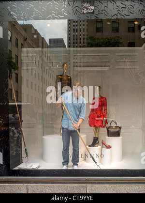 In einem Bürgersteig-Fenster von Saks Fifth Avenue Spezialität bereitet-Store in New York ein Schaufenster-Dekorateur ein neues Display. Stockfoto
