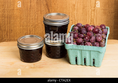 Stachelbeere-Gelee und rote Stachelbeeren auf Holztisch Stockfoto