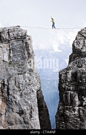 Mann zu Fuß eine Highline zwischen zwei Felsen, Schilthorn, Berner Oberland, Kanton Bern, Schweiz Stockfoto