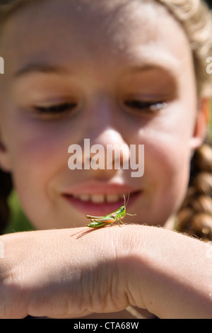 Mädchen (8 Jahre) mit Heuschrecke auf Hand, Bayern, Deutschland Stockfoto