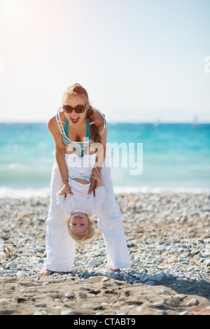 Mama spielt mit Baby am Strand Stockfoto